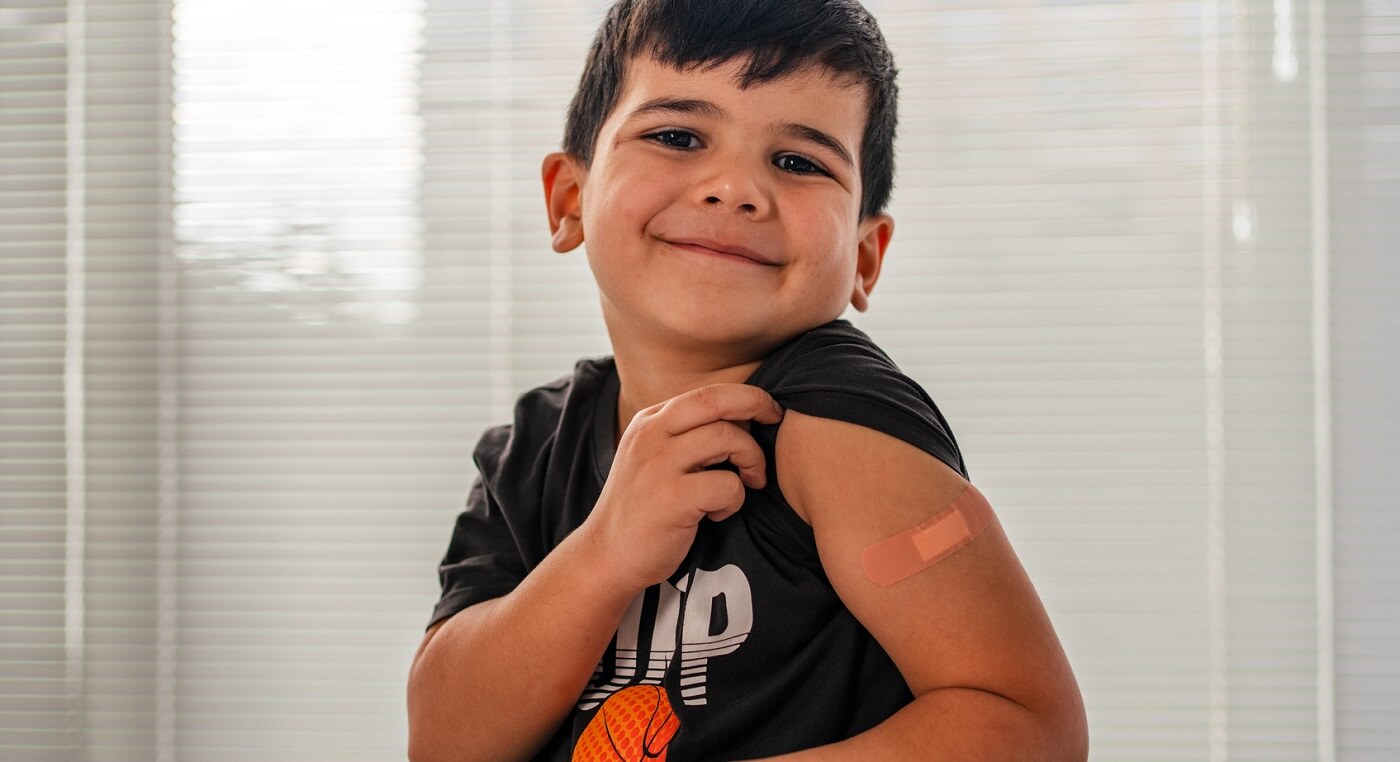 Photo of smiling little boy showing that he got his vaccine.