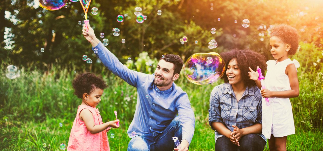 A father and mother make giant bubbles with their two daughters