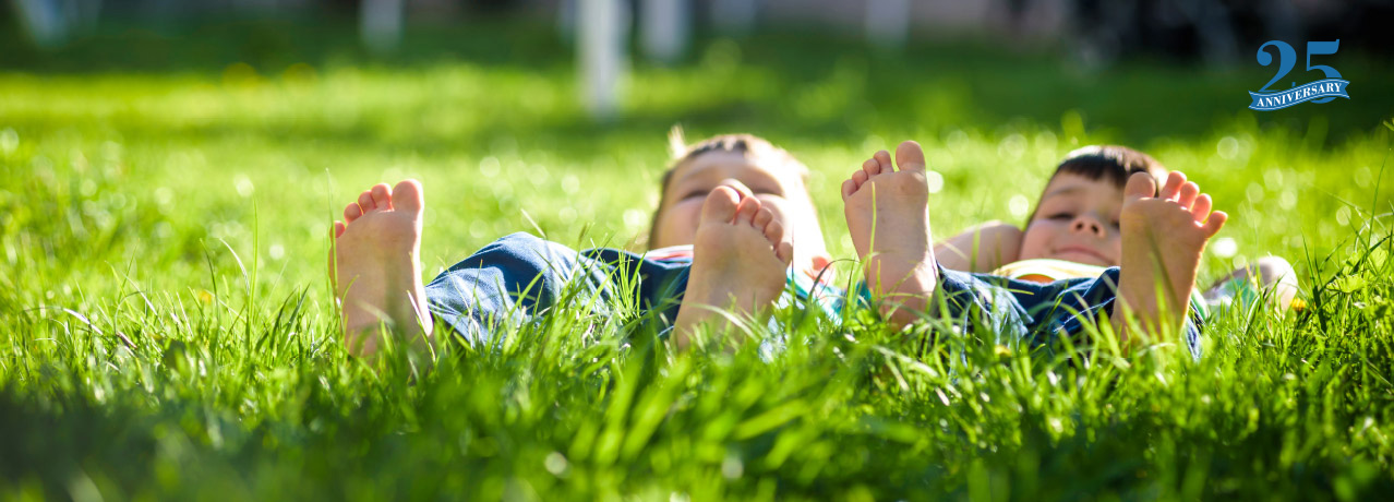 Photo of barefoot little boys lying in grass.
