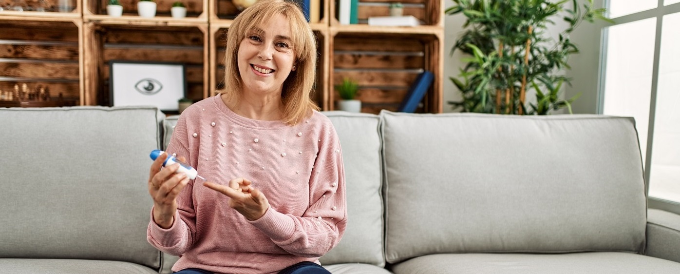 Middle age woman measuring blood glucose at home.