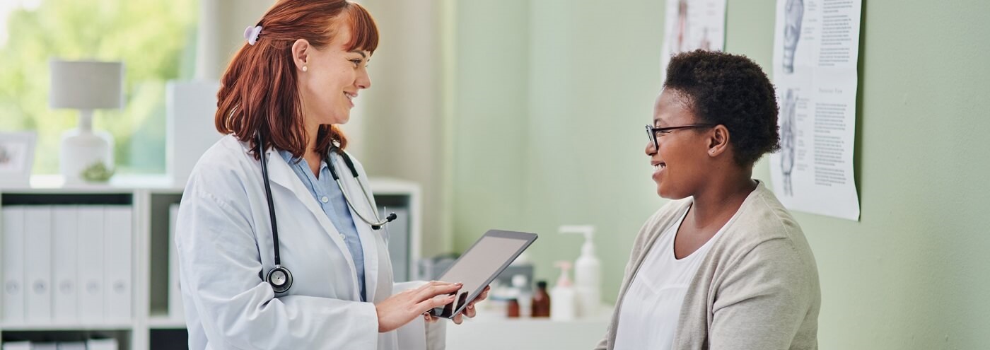 Image of woman sitting on examination table and talking to her doctor.