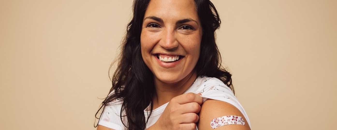 Smiling woman showing her vaccine band-aid.