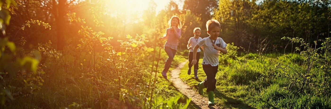 Photo of happy young children running down a trail on sunny day.