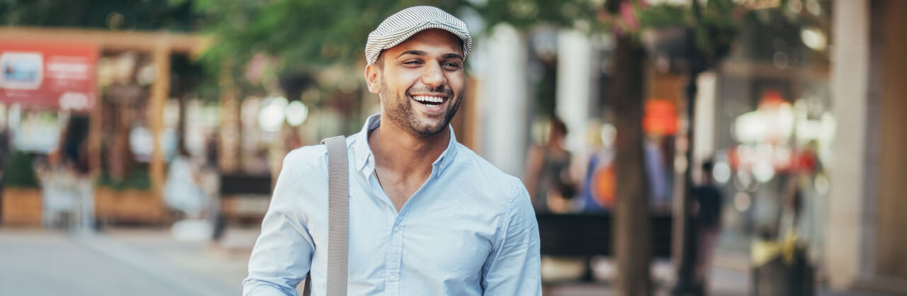 Man with a hat walking down the street and smiling