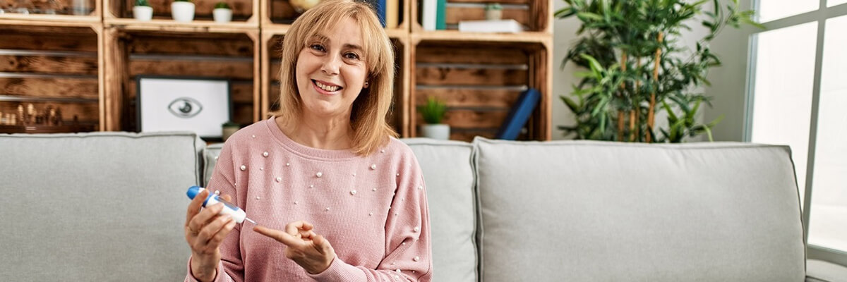 Middle age woman measuring blood glucose at home.