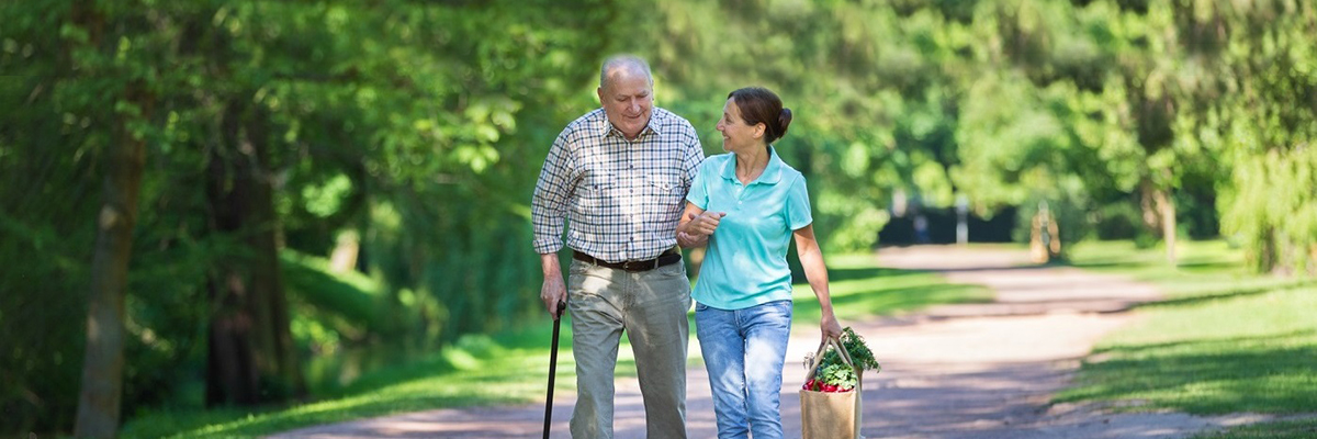 Elderly couple walking with bag of groceries