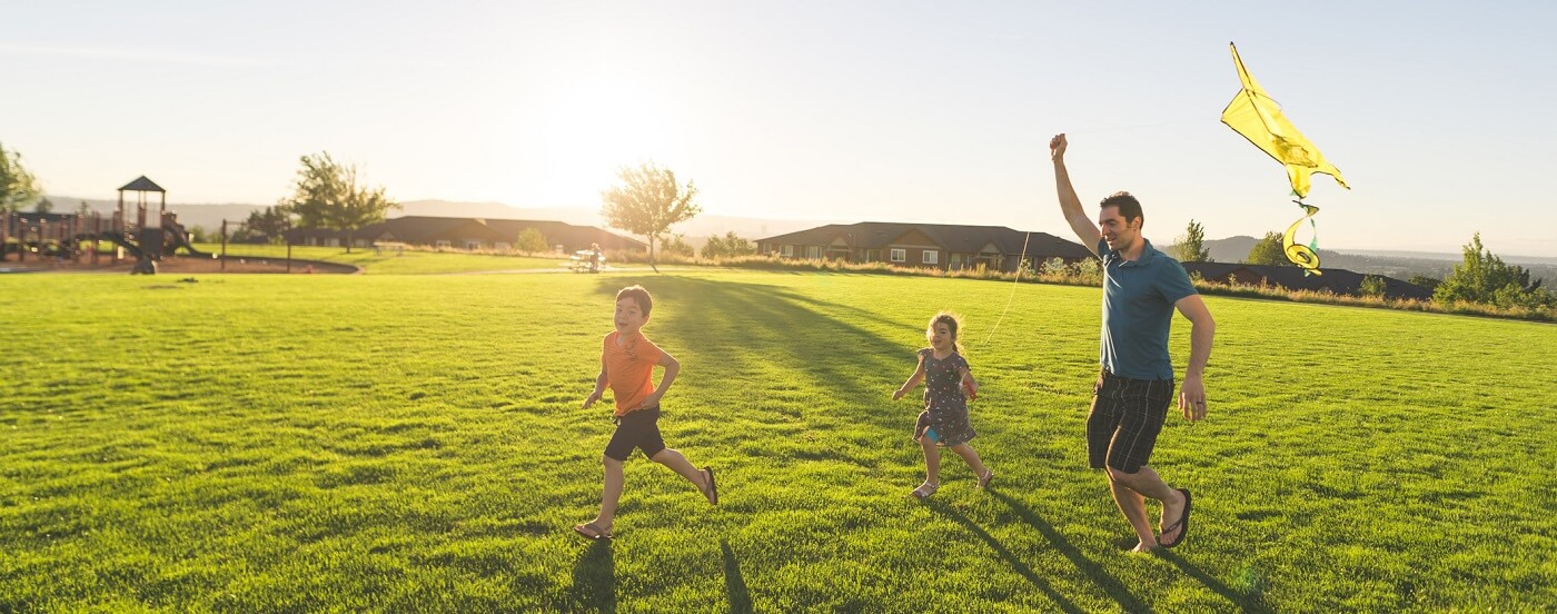 Photo of two children flying a kite with their father.