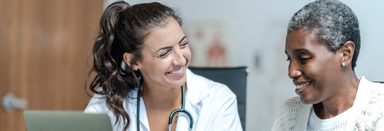 two healthcare workers talk in front of a computer