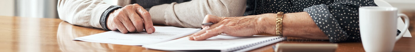 Photo of a couple signing living will paperwork.