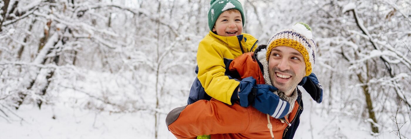 Father with young son outdoors on a snowy day.