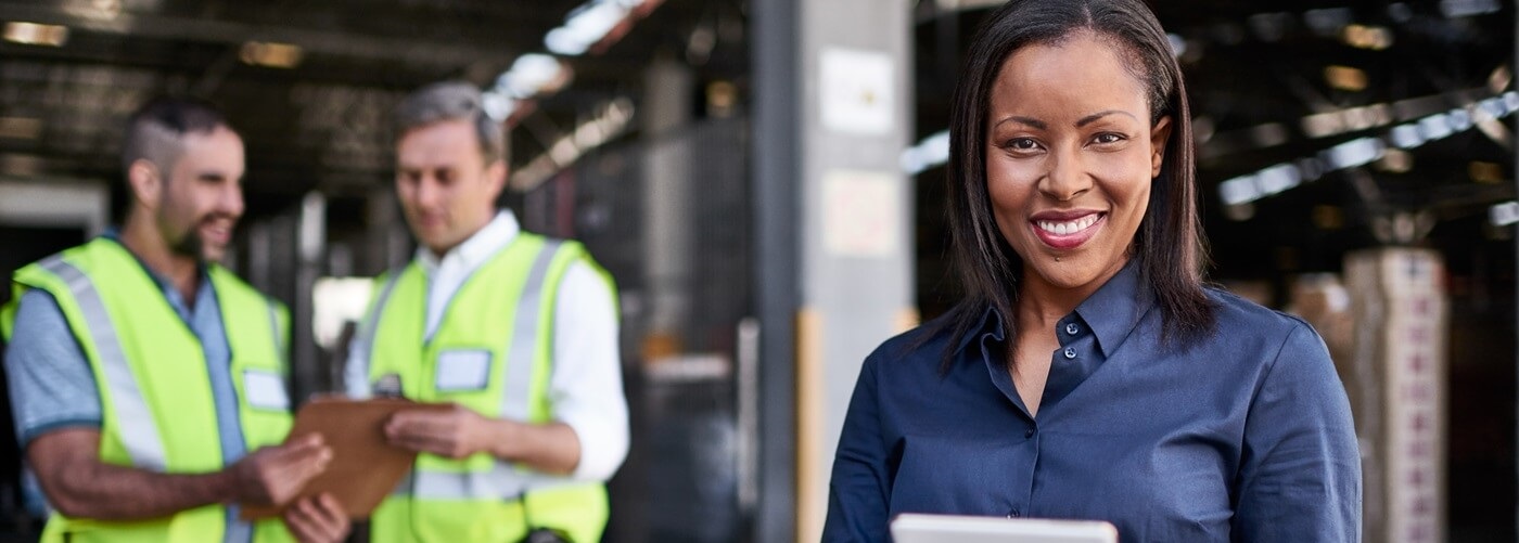 Warehouse manager with employees nearby.