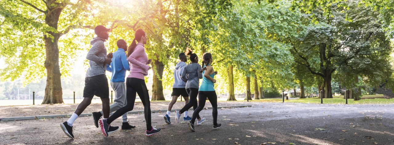 A group of people run through a city park