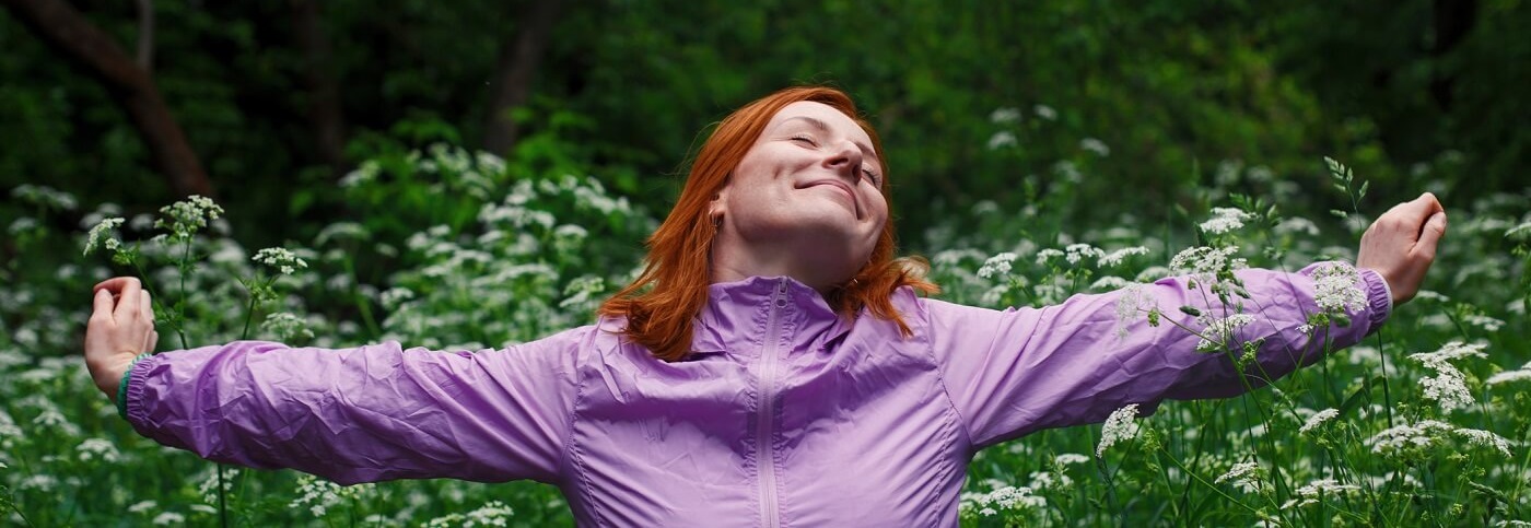 Happy woman standing outdoors and breathing deeply.