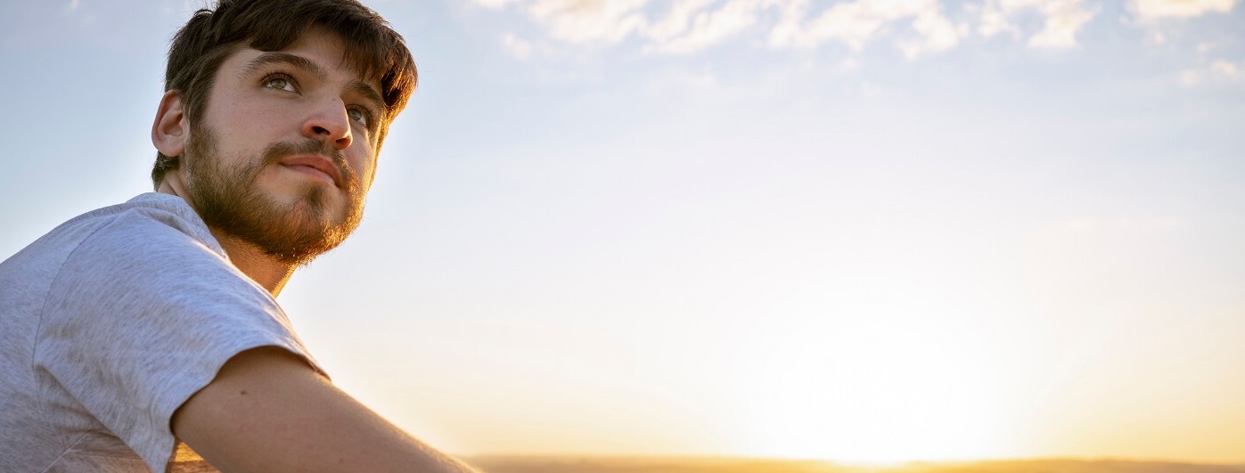 Photo of young man looking thoughtfully outward.