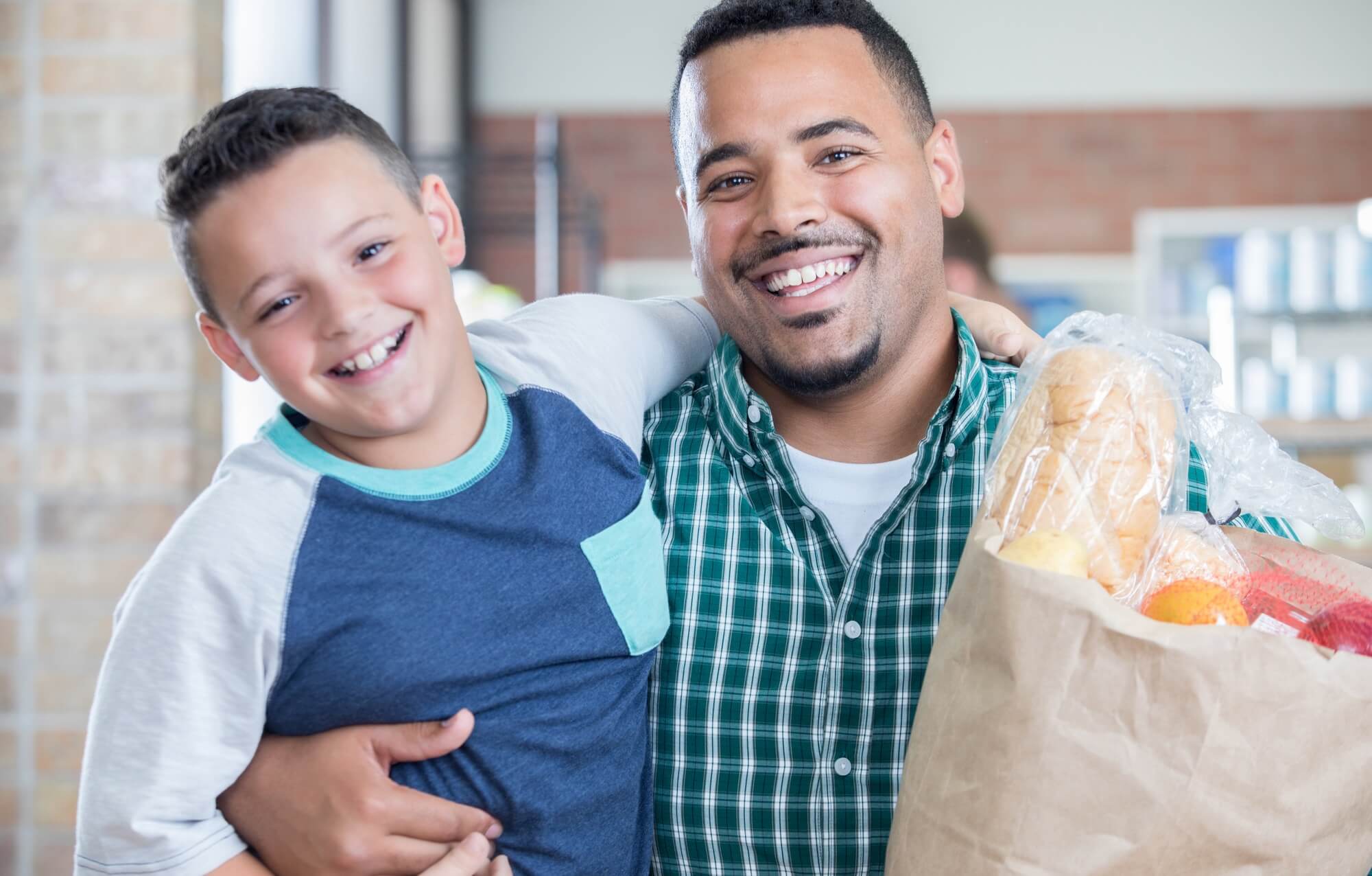 Father and son with bag of groceries.