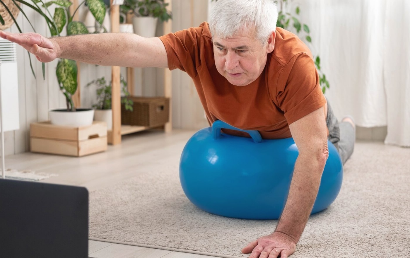 Senior man doing physical therapy exercises using a tablet for instruction.