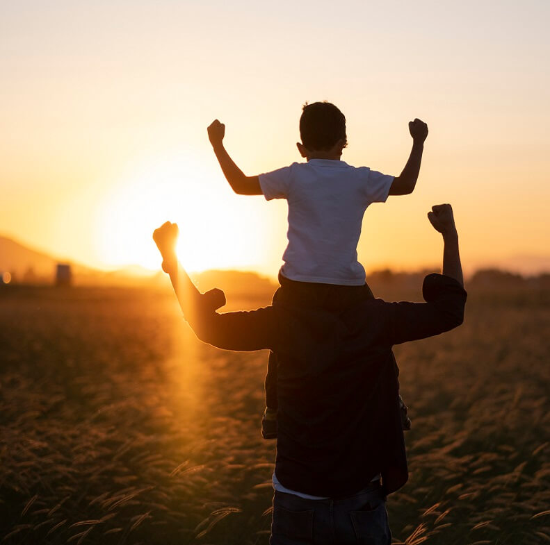 Photo of young boy riding on dad's shoulders.