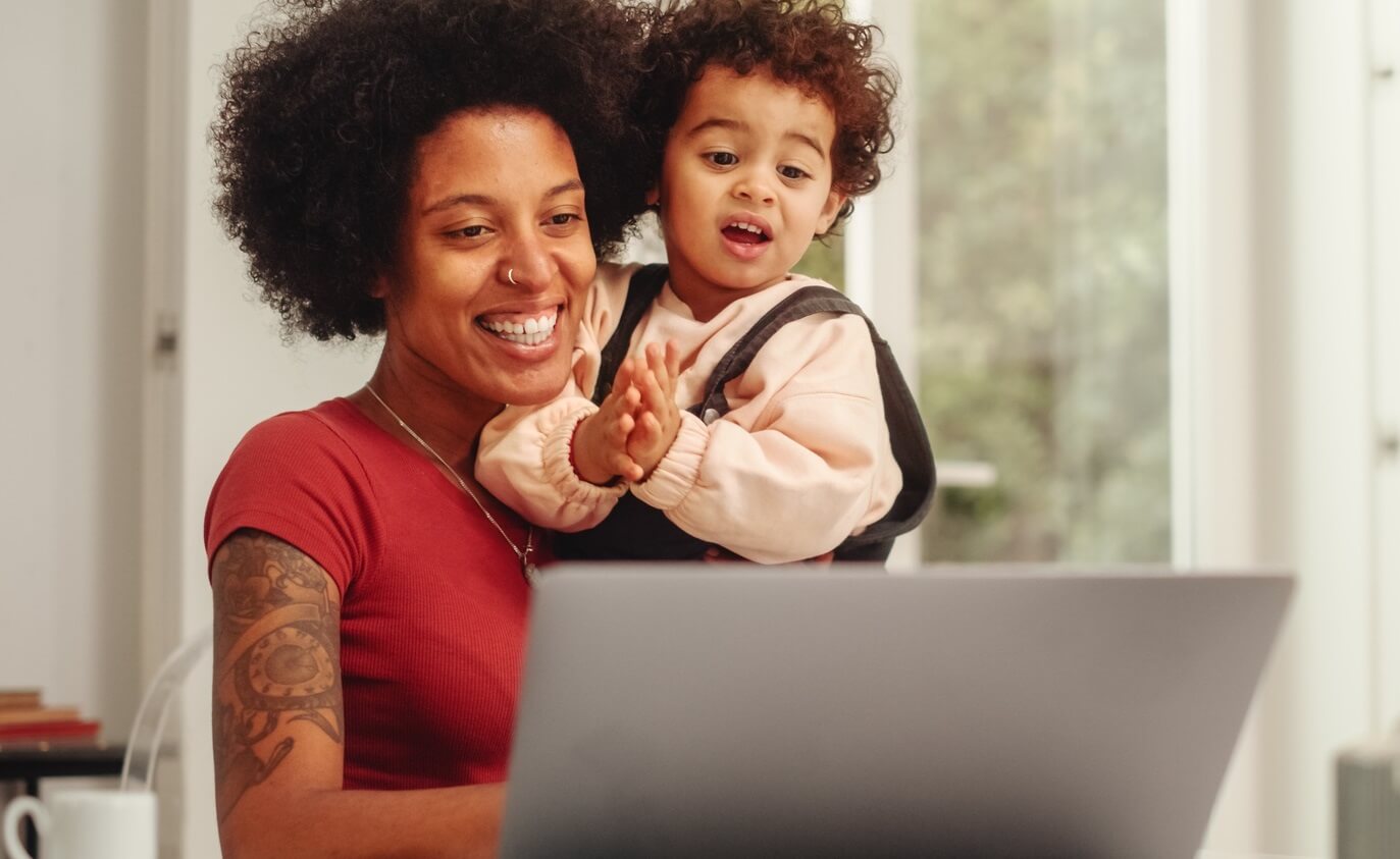 Young mom looking up information on laptop with child in her lap.