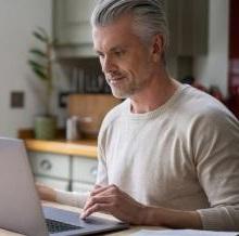 Photo of man looking up information on his laptop.