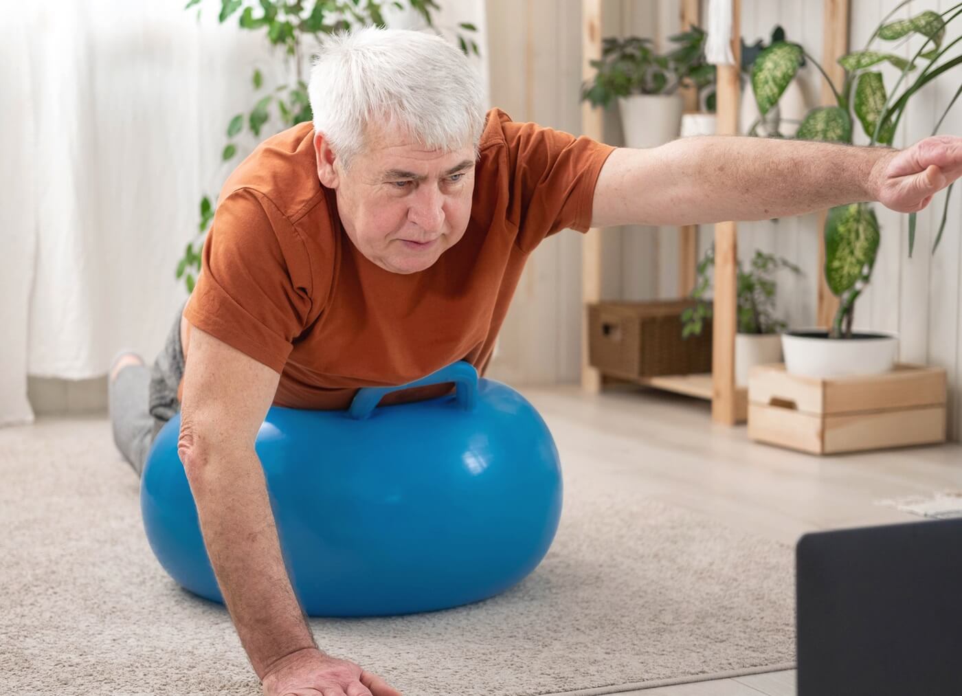 Senior man doing physical therapy exercises using a tablet for instruction.