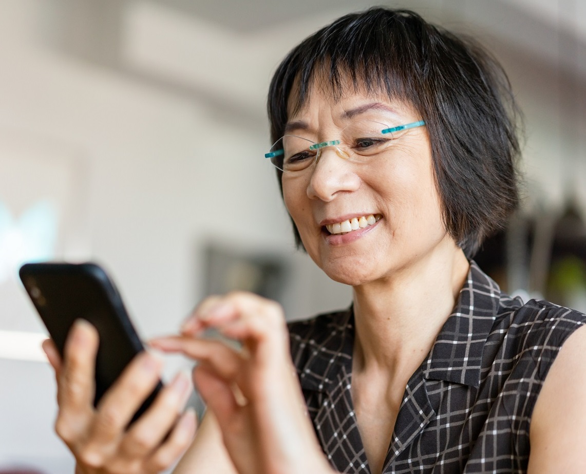 Photo of woman using MyDHMP Member Portal on her cell phone.