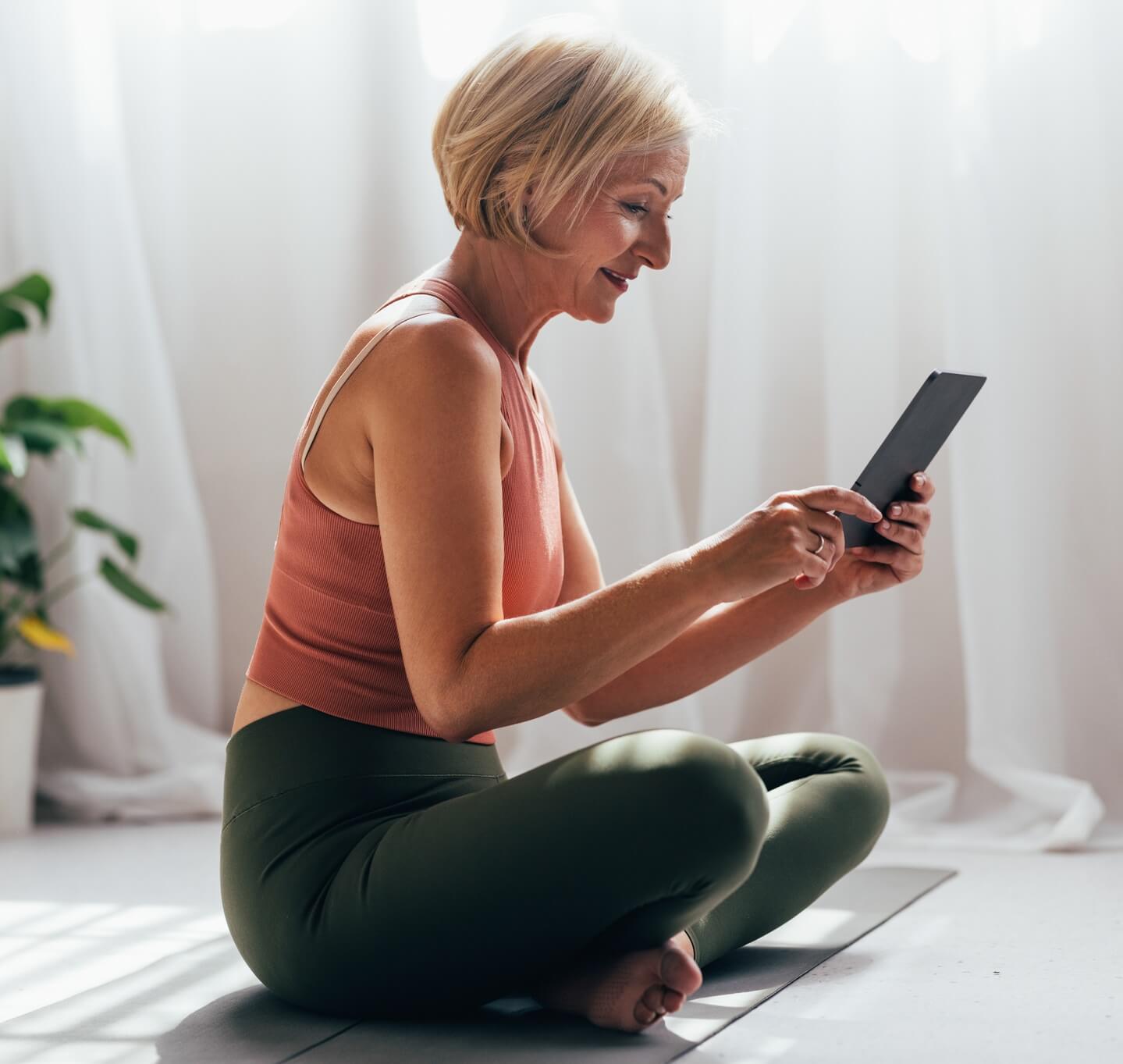 Woman exercising at home with tablet.