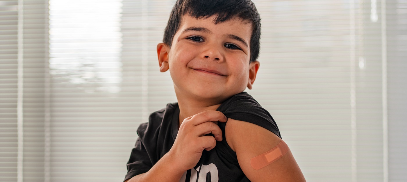 Little boy showing his vaccine bandaid.