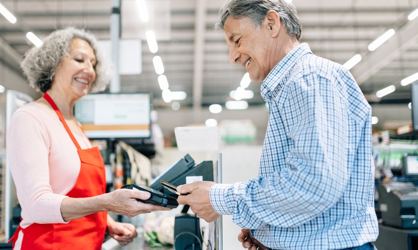 Senior man at the checkout counter paying with a FlexCard.