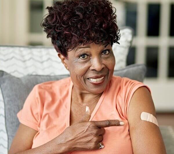 Woman showing her bandaid after getting a flu vaccine.