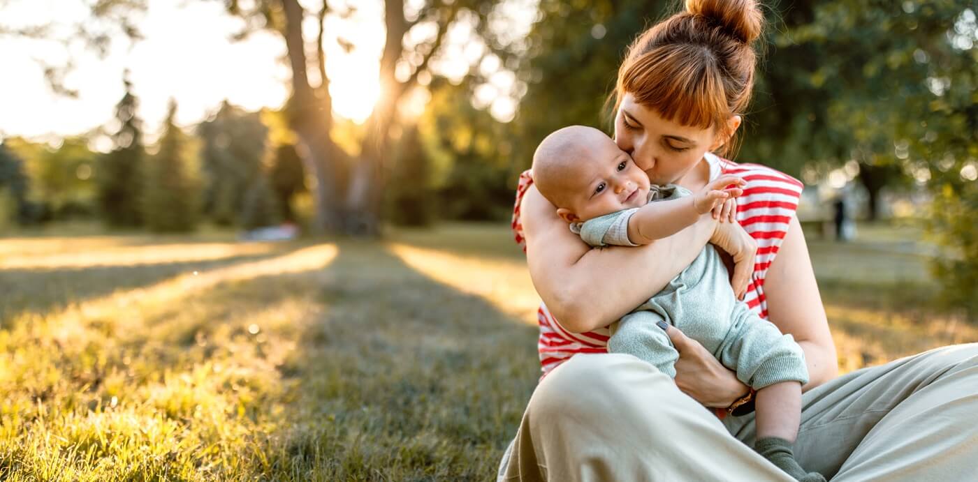 Young mother holding her baby outdoors.