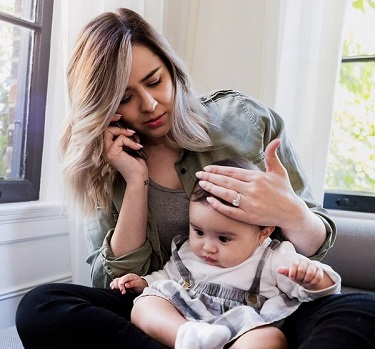 Image of worried mom with sick baby calling doctor