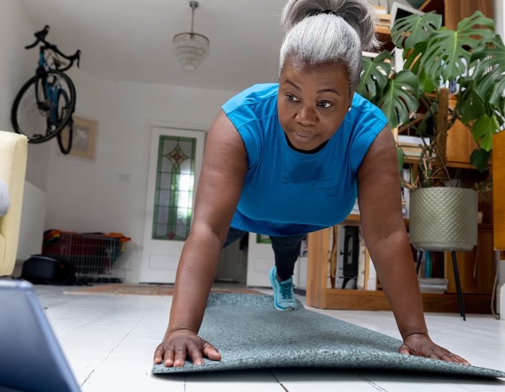 Senior woman doing planks at home.