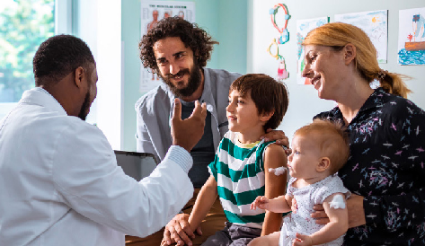 A mother and father sit with their two children at a visit to the pediatrician