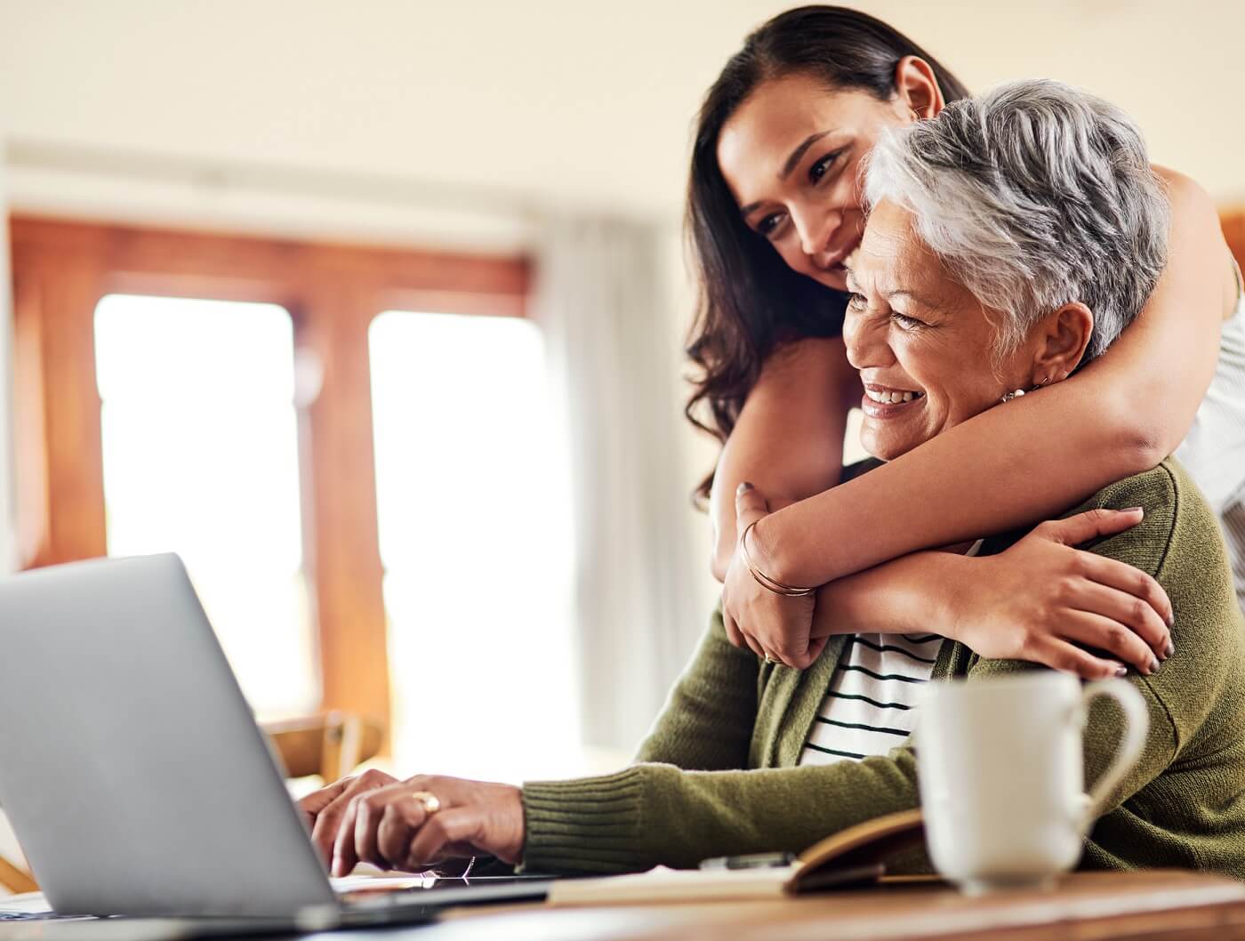 Woman shopping for health insurance online with her daughter looking on.