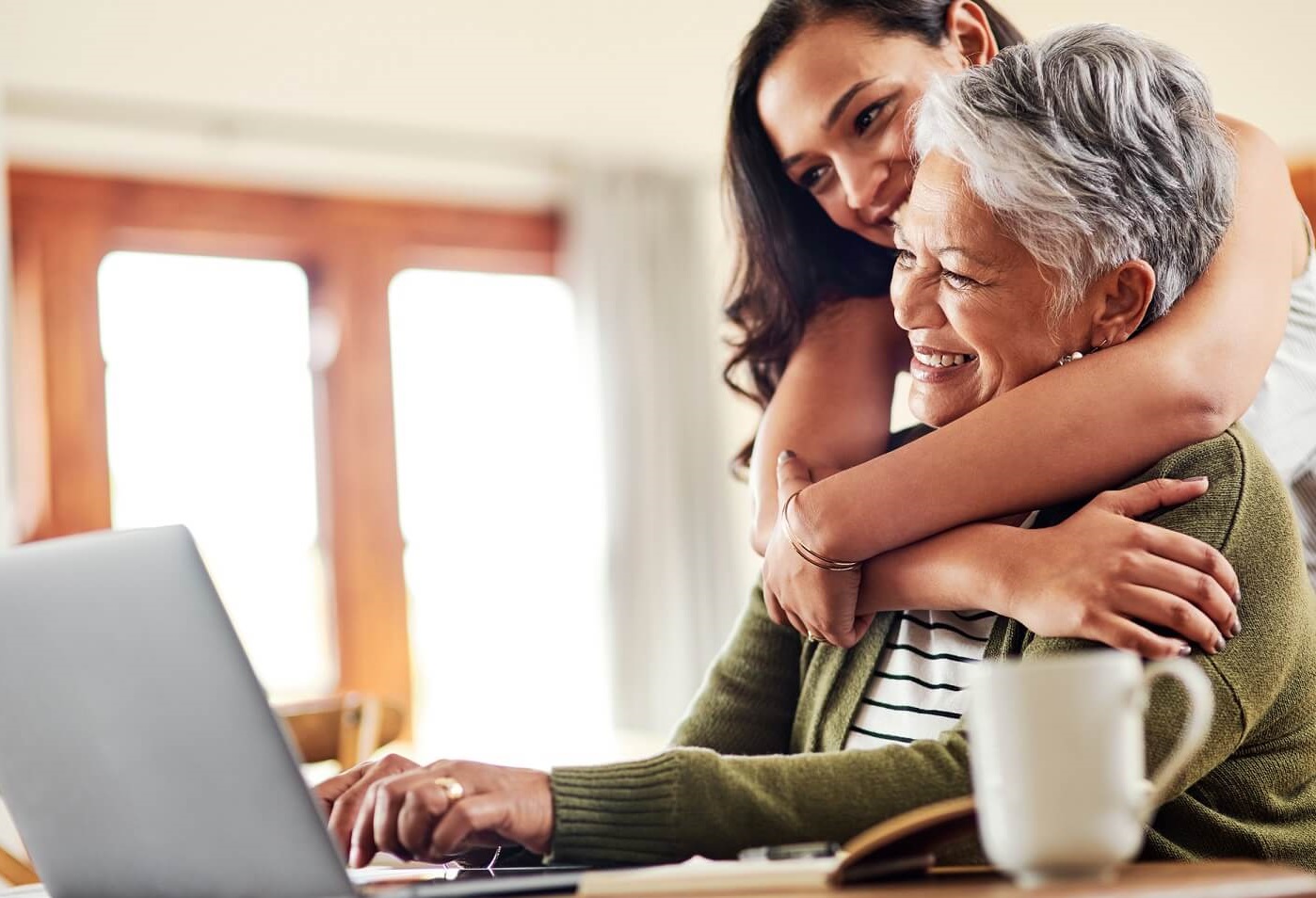 Woman shopping for health insurance online with her daughter looking on.