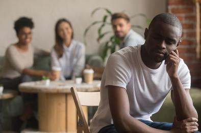 Man sitting alone with 3 people sitting in the distance