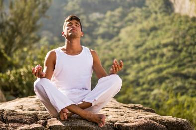 man doing yoga on rock