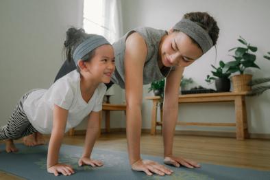 A young mother and her daughter exercise on a yoga mat