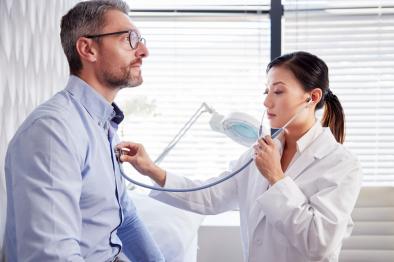 a female doctor listens to a mans heart with her stethescope