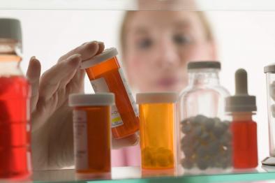 Woman looking at medicines in medicine cabinet.