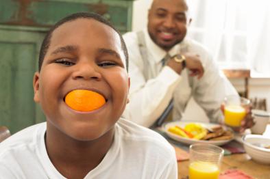 Little boy eating orange.