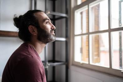 Photo of man looking out window thoughtfully.