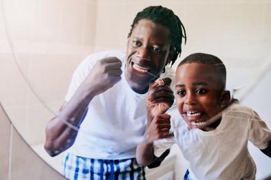 Father and son flossing teeth together.