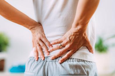 Photo of person stretching and holding their back due to pain.