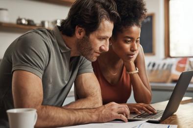 Photo of couple looking intently at laptop screen.