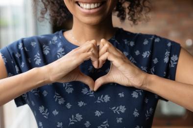 Photo of smiling young woman making shape of heart with her hands.