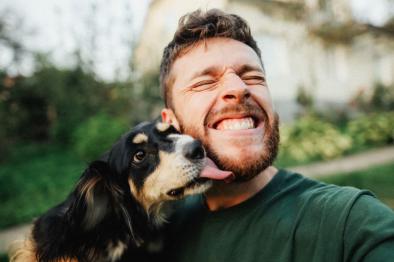 Photo of dog kissing smiling guy