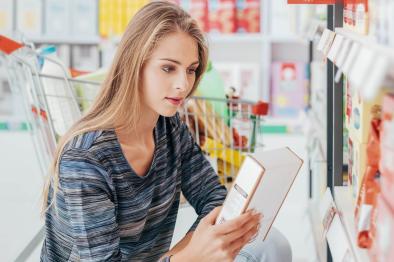 Photo of young woman reading food nutrition label.