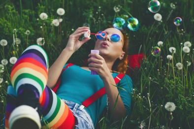 Image of colorfully-dressed woman blowing bubbles.