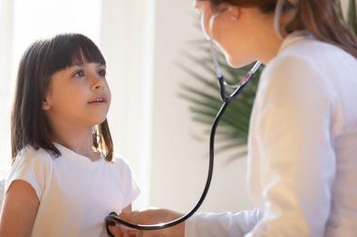 Photo of health care provider listening to child breathing with stethoscope.